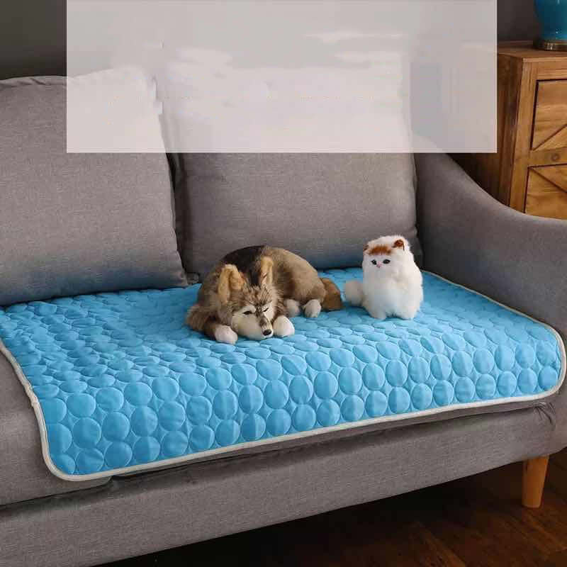 Summer cooling mats for pets on a couch with a dog resting and a plush toy.