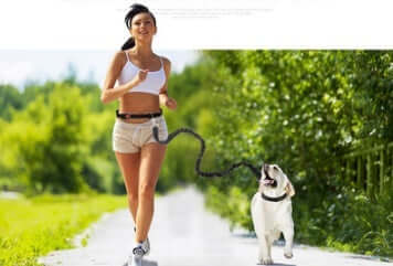 Woman jogging with a dog using a hands-free dog leash for jogging in a scenic outdoor setting.