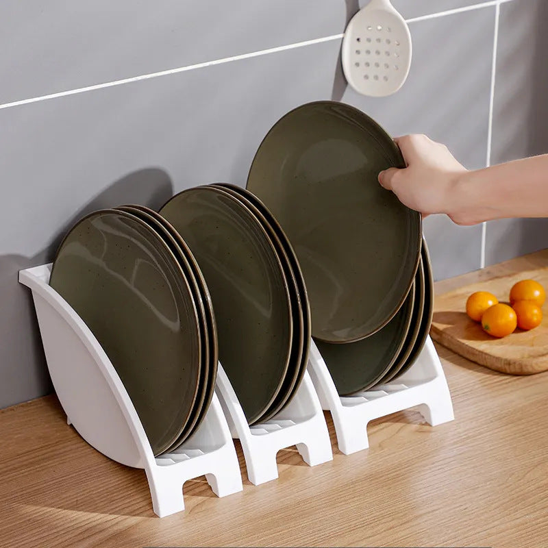 A person placing a plate on a multifunctional kitchen tableware rack with multiple plates arranged neatly.