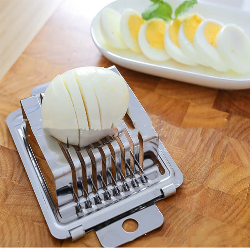 Stainless Steel Egg Cutter used for slicing boiled eggs with precision, showcasing its stainless steel design on a wooden surface.